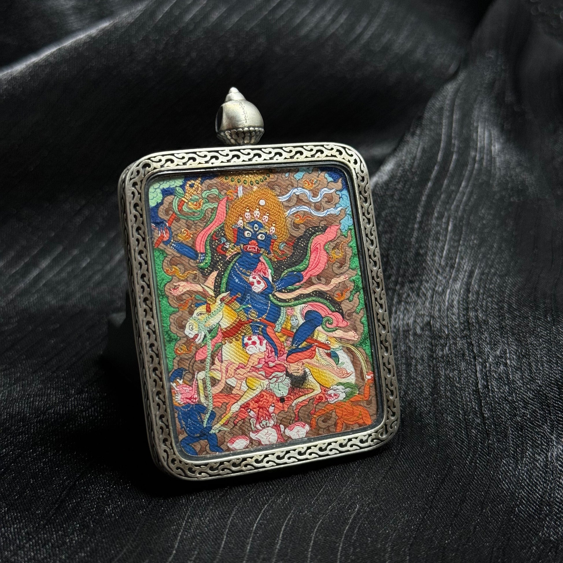 Close-up detail of a hand-painted Palden Lhamo mini thangka pendant highlighting fine line work, mineral pigment texture, and expressive deity imagery.