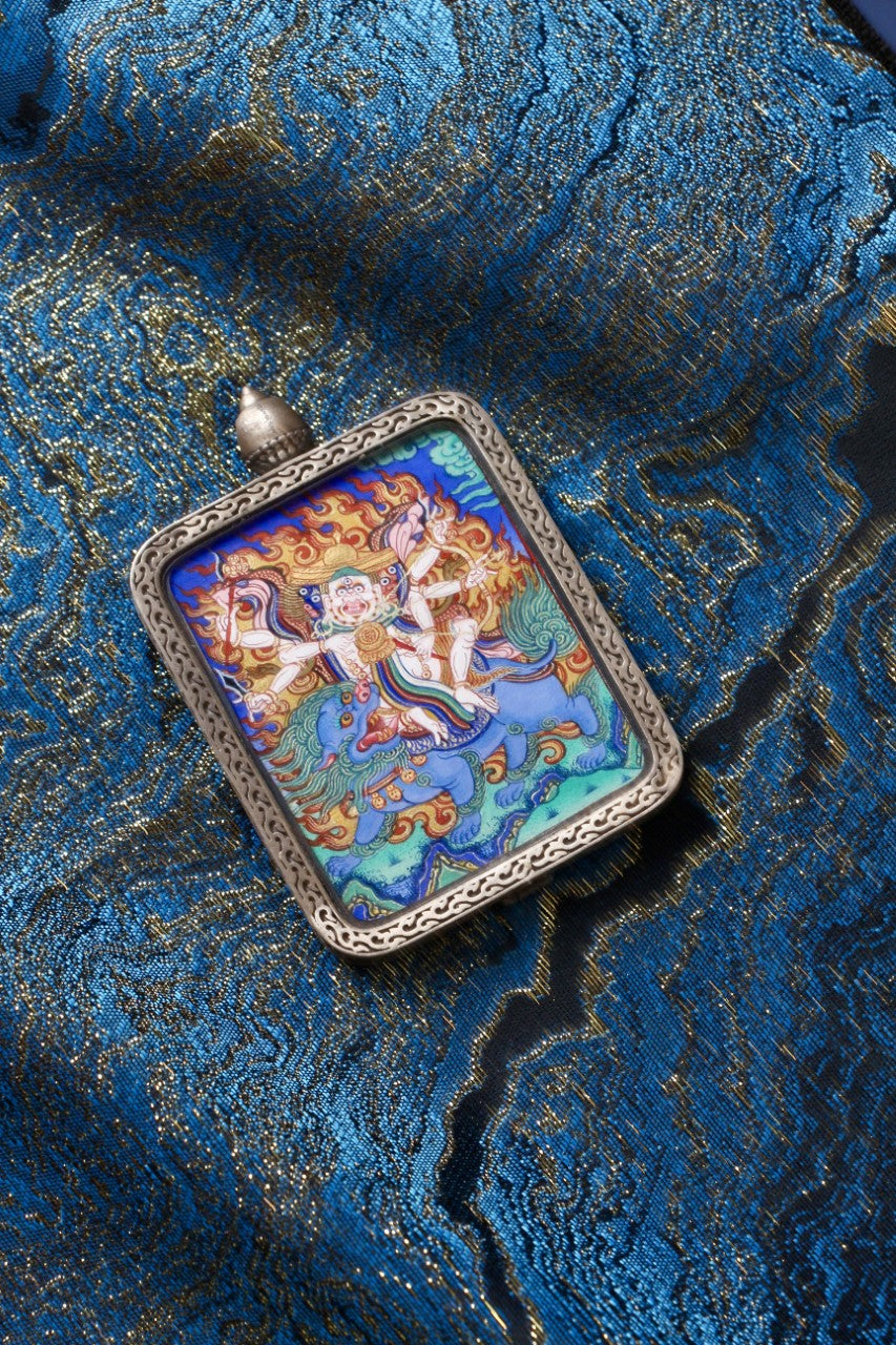 Hand-painted Pehar Gyalpo mini thangka pendant from Rebgong, depicting the Tibetan protector deity riding a lion, set in a Nine-Colored Deer silver case
