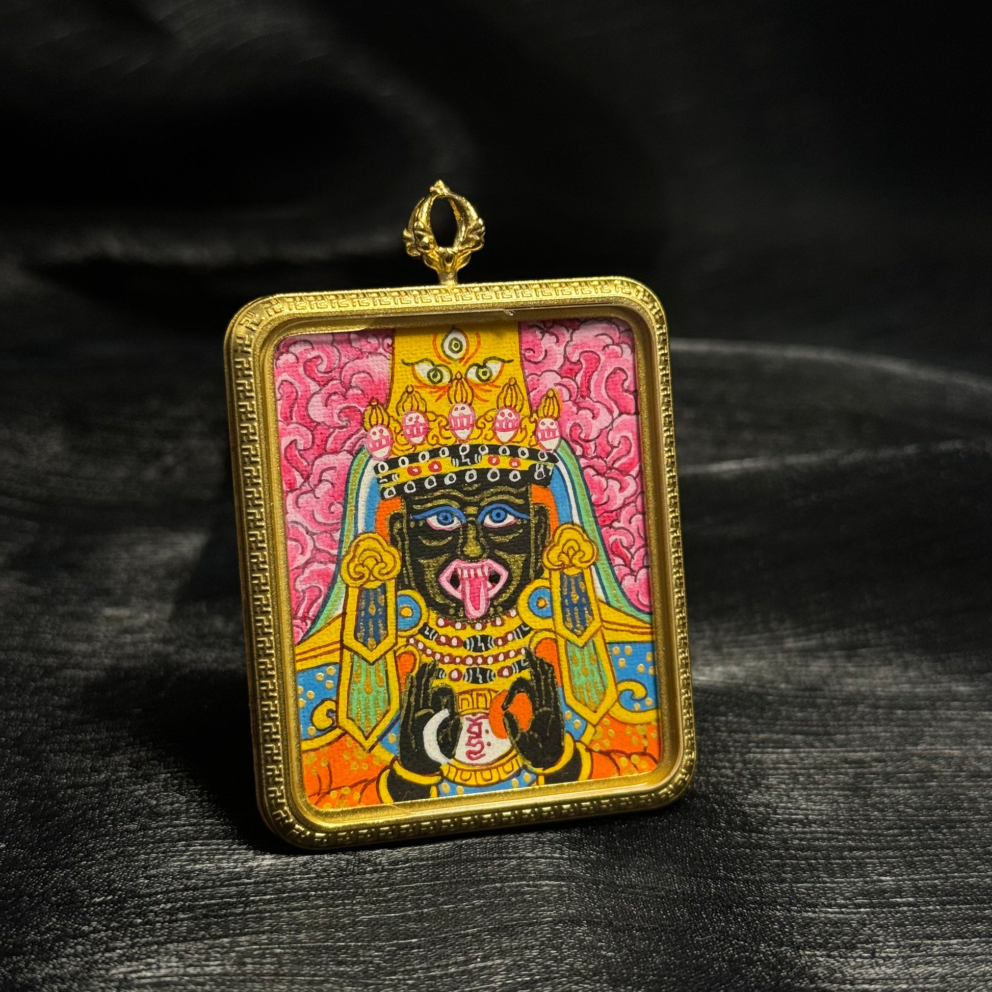 Side angle view of hand painted pink Zaki Lhamo mini thangka pendant from Nepal showing detailed deity portrait, bright mineral pigments and square gold frame on miniature portable Buddhist artwork.
