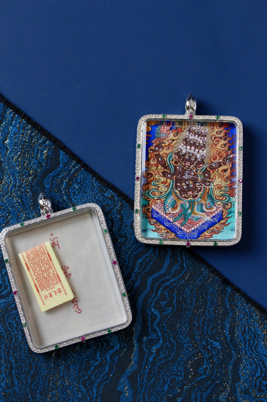 Open and closed views of a Rahu (Rahula) double-sided Gawu pendant; hand-painted Rebgong thangka image on the front with a 925 silver case, and a mantra insert compartment shown open on blue brocade fabric.
