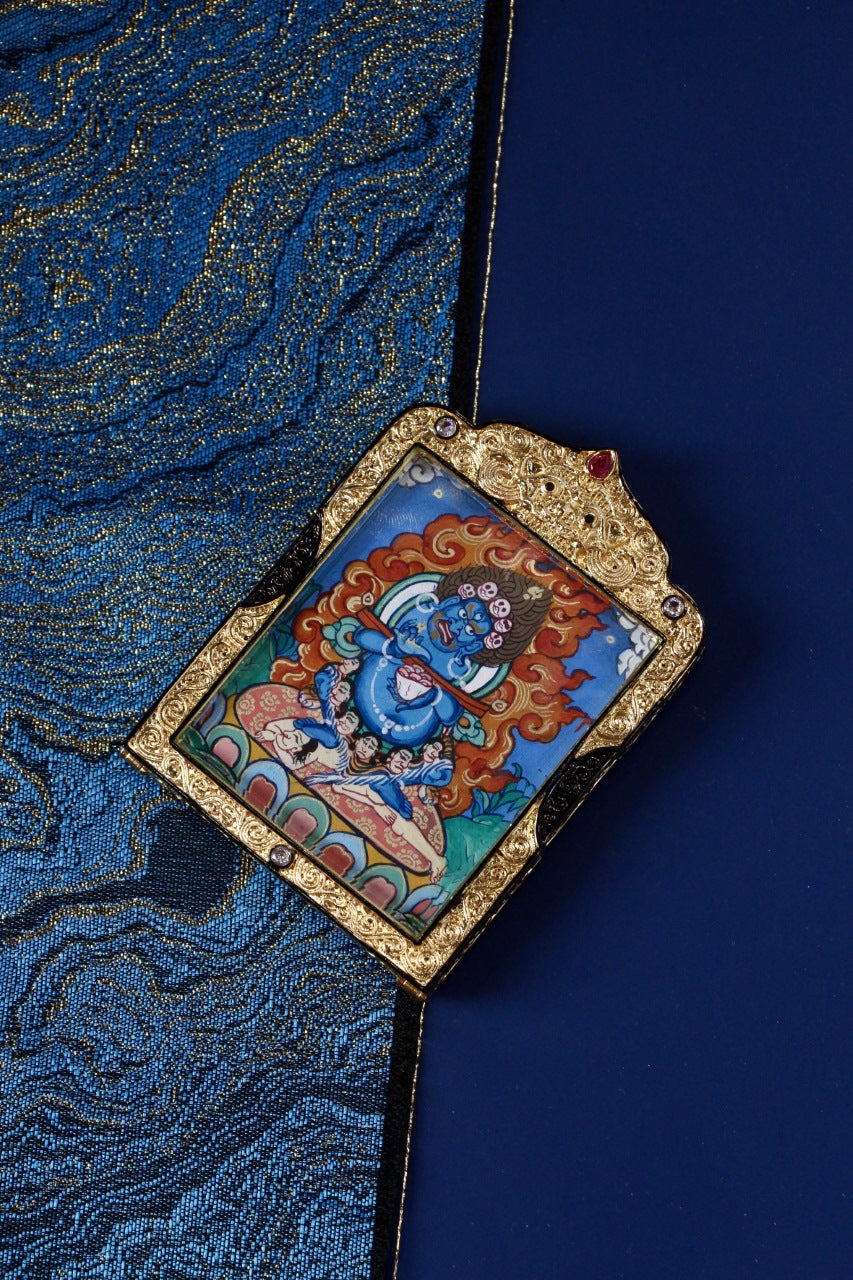 Angled view of Rebgong Baizhang Mahakala gawu pendant, traditional Rebgong thangka art, double-sided hand-painted, black-gold copper frame, 4 × 5 cm