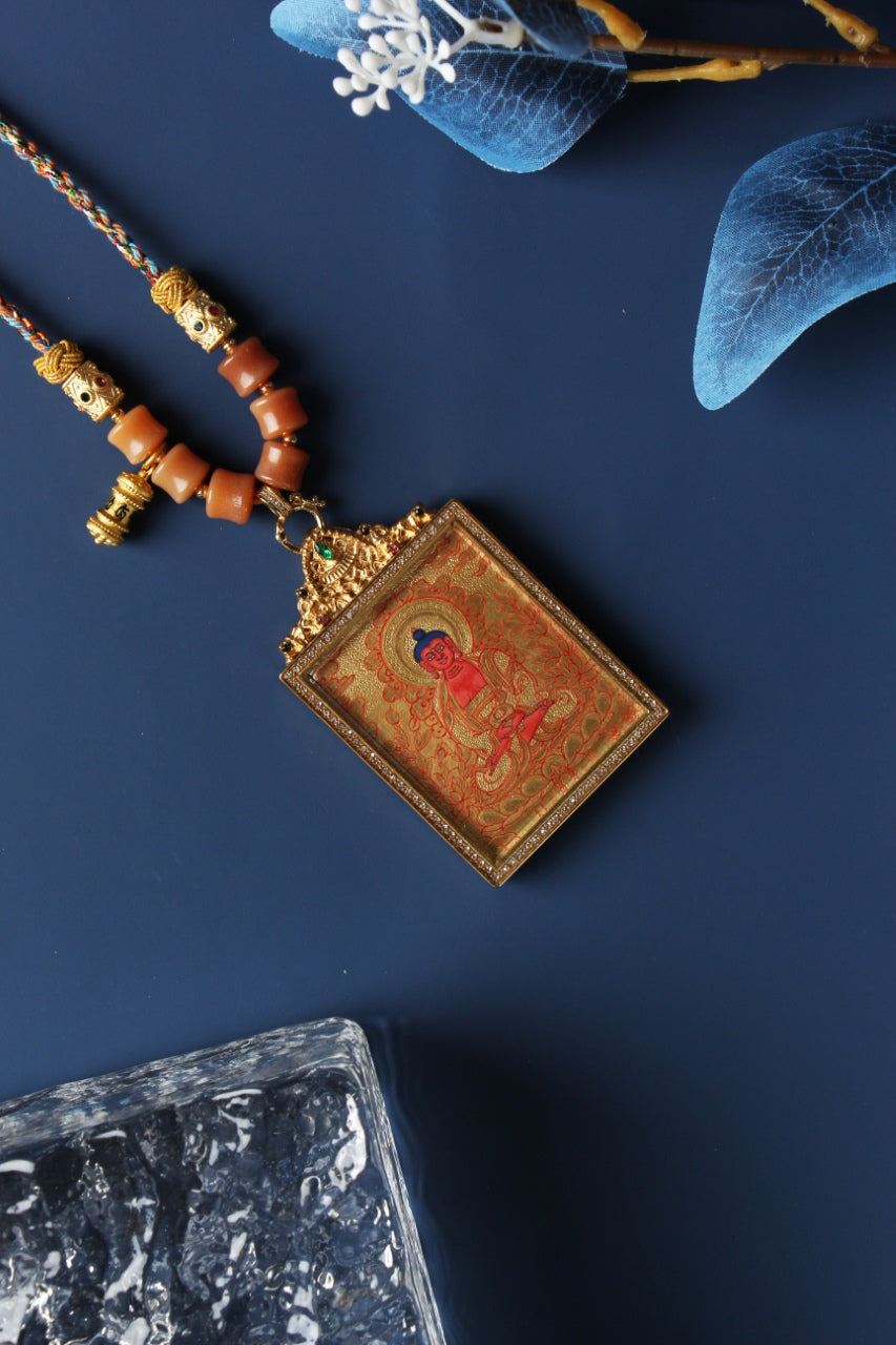 Close-up view of Amitabha Buddha thangka pendant showing fine gold thangka linework, layered mineral pigments, gemstone-accented titanium steel frame, and detailed top bail structure