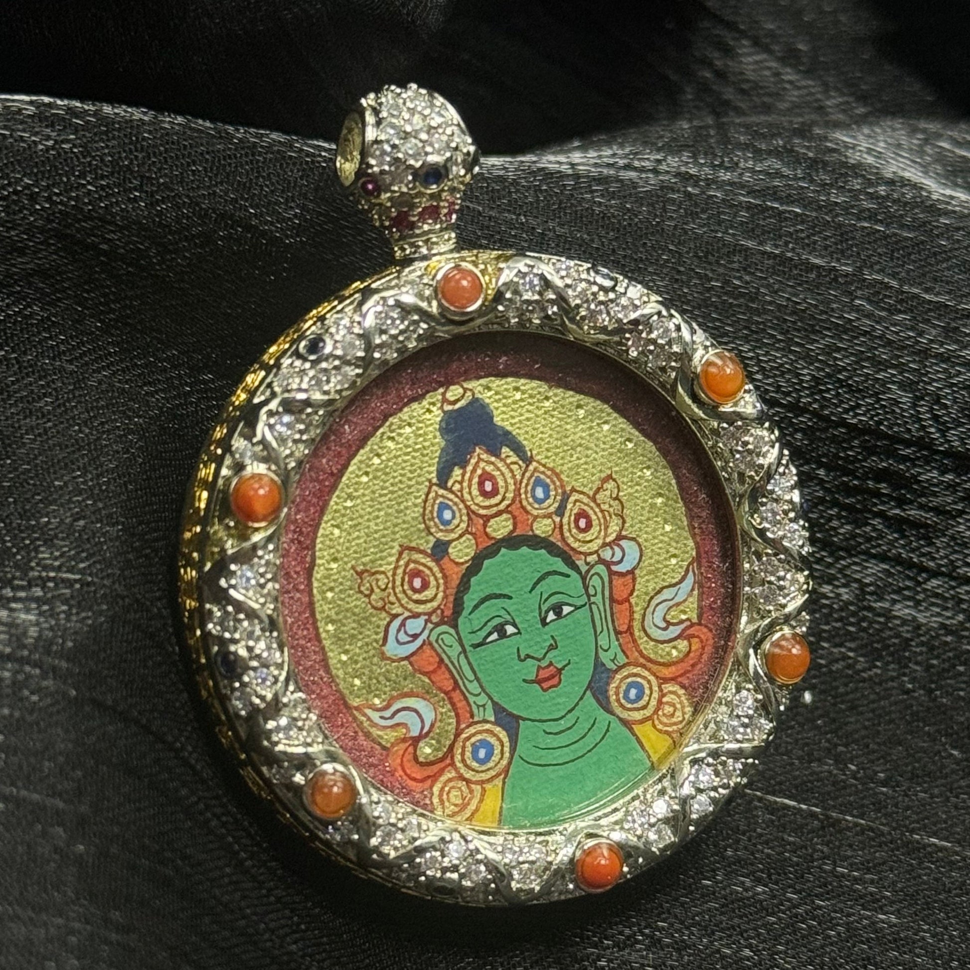 Close-up detail of a Rebgong-style Green Tara thangka showing serene facial features, cinnabar red background, and layered gold powder halo