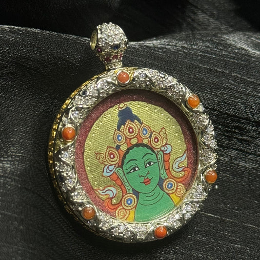 Close-up detail of a Rebgong-style Green Tara thangka showing serene facial features, cinnabar red background, and layered gold powder halo