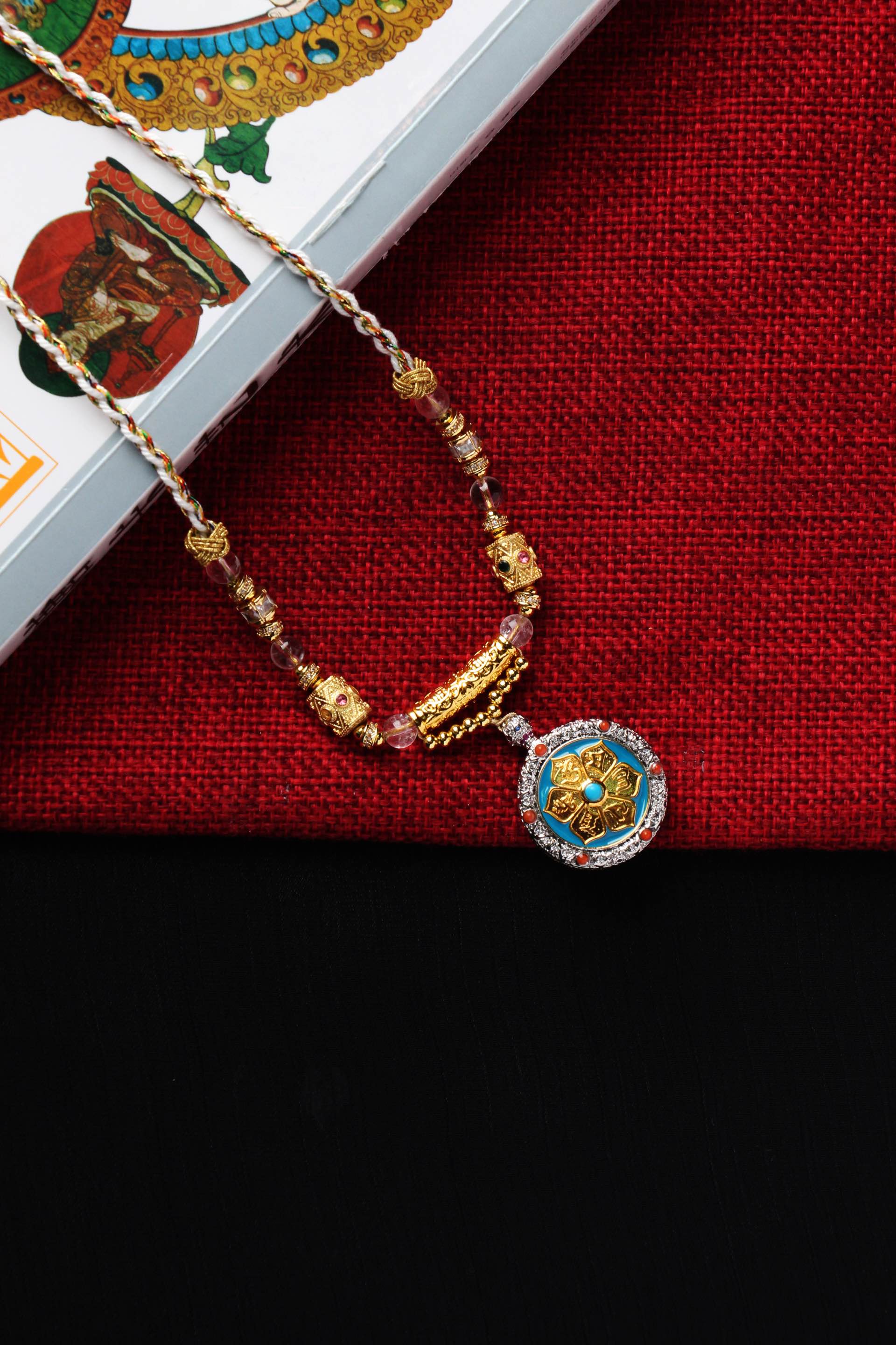 Hand-painted Rebgong style Avalokiteshvara mantra pendant showing lotus base, gold powder calligraphy, and detailed metal setting