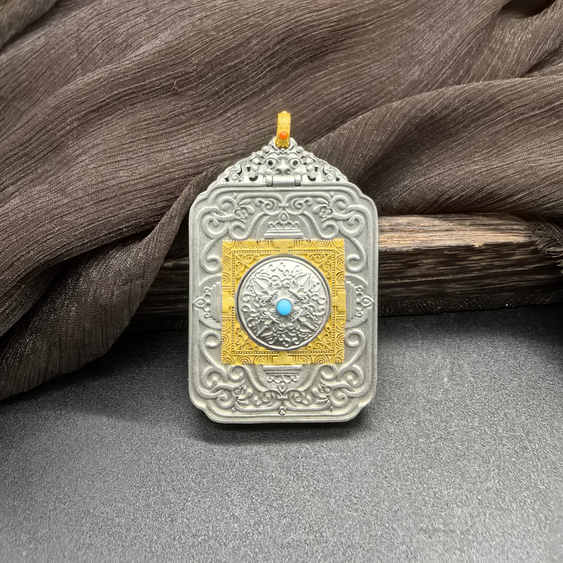 Back view of the Rebgong series mini thangka pendant showing the standard protective amulet design used across the series, featuring an engraved ornamental pattern with a central turquoise-style stone set in a detailed metal frame.
