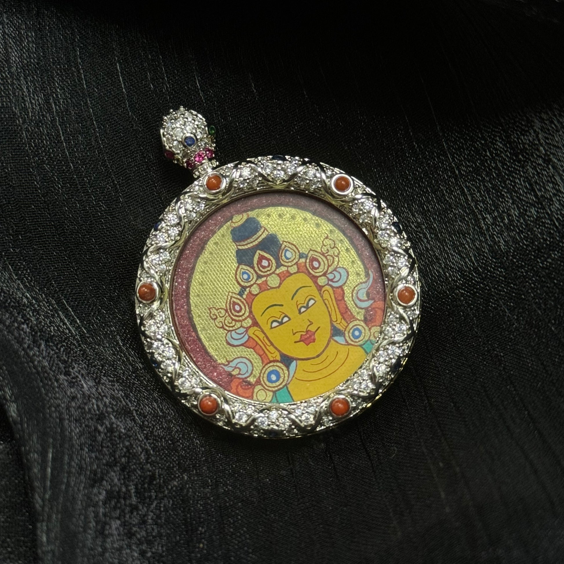 Rebgong style miniature thangka pendant depicting Manjushri Bodhisattva face with traditional Tibetan mineral pigment painting and decorative gemstone copper frame.