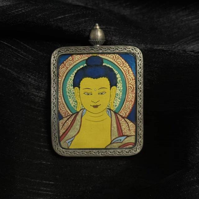 Detailed front view of Shakyamuni Buddha thangka pendant showing traditional Buddhist portrait and layered mineral pigment colors