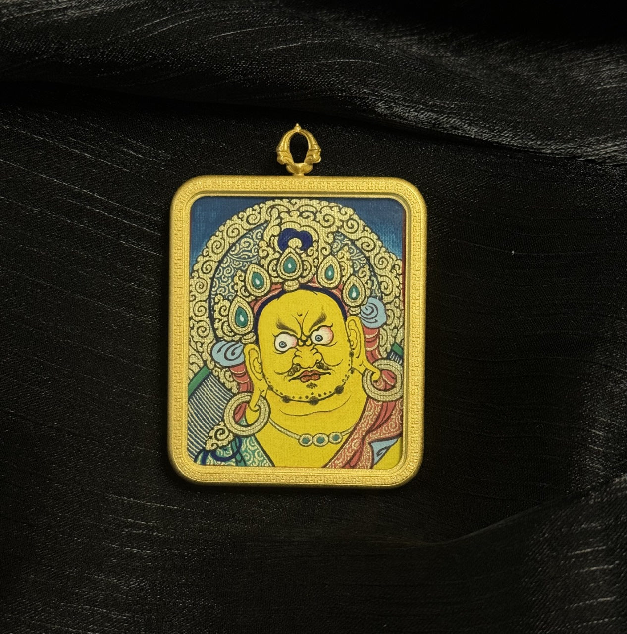 Detailed front view of Yellow Jambhala thangka pendant showing layered mineral pigment colors and traditional Buddhist iconography