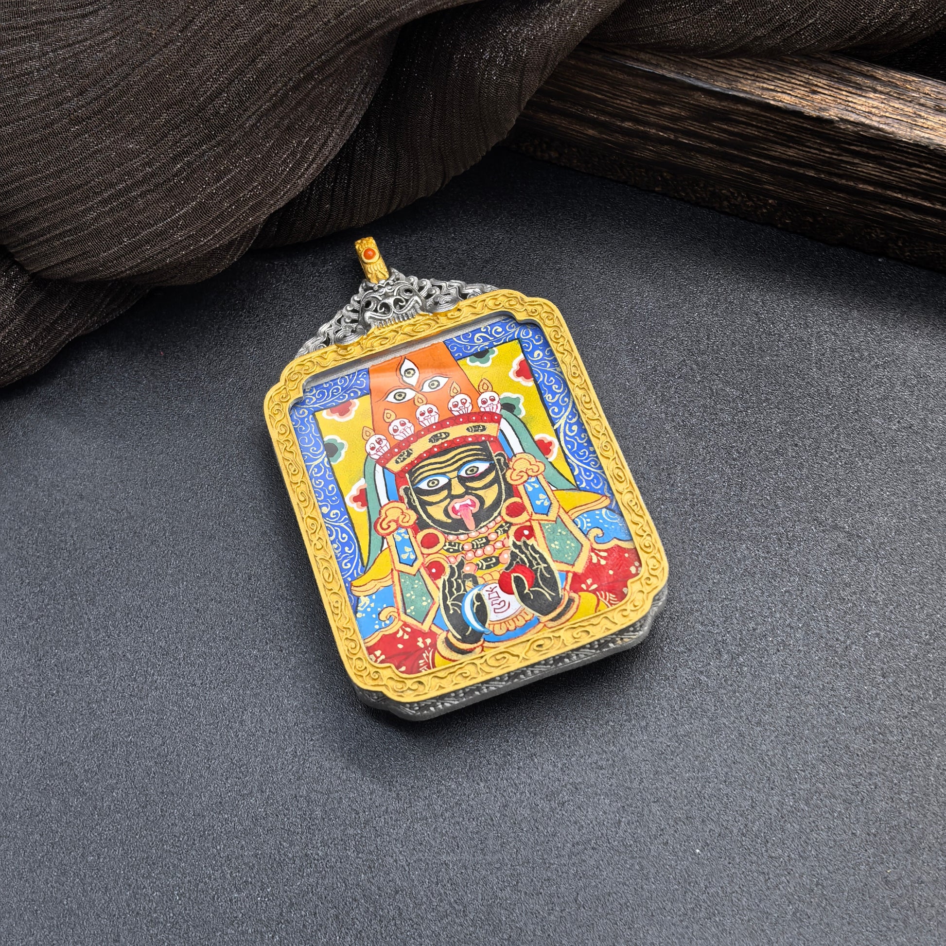 Close angled display of Zaki Lhamo mini thangka pendant highlighting detailed Rebgong hand-painted lines, deity facial features, ritual objects and bright mineral pigment colors.