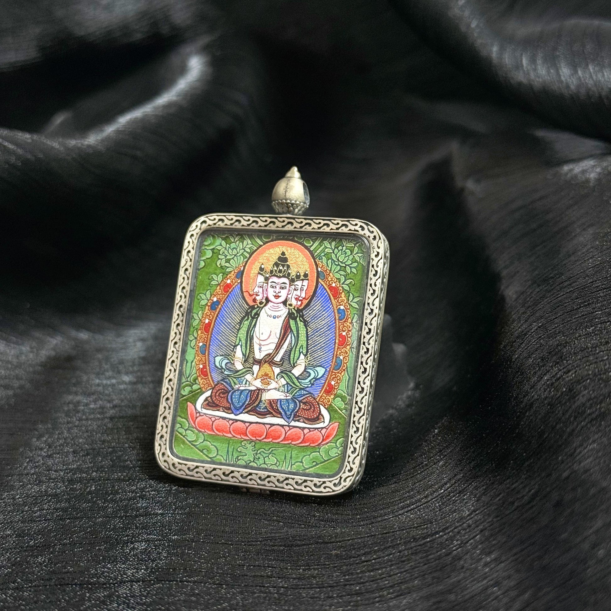 Hand-painted Tibetan Vairocana Buddha miniature thangka pendant set in a detailed silver frame.