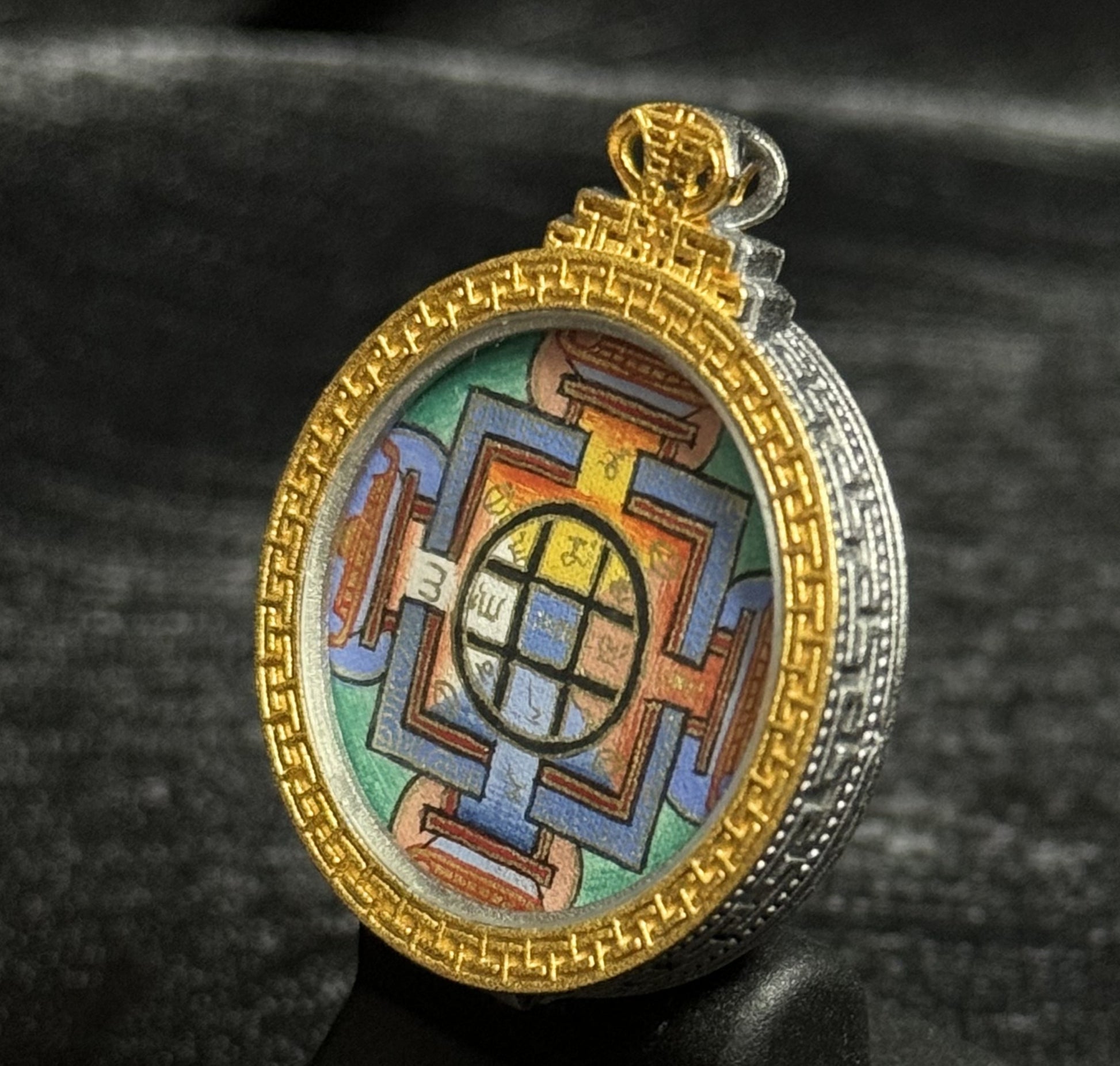 Side view of Yamantaka Mandala mini thangka pendant showing hand-painted mandala artwork set within a gold and silver decorative pendant casing.