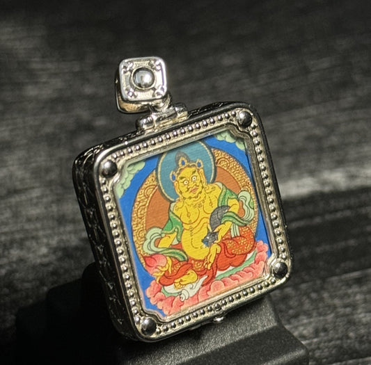 Angled view of Rebgong Yellow Jambhala mini thangka pendant showing fine metal case details, hand-painted mineral pigments, designed for collection and inheritance