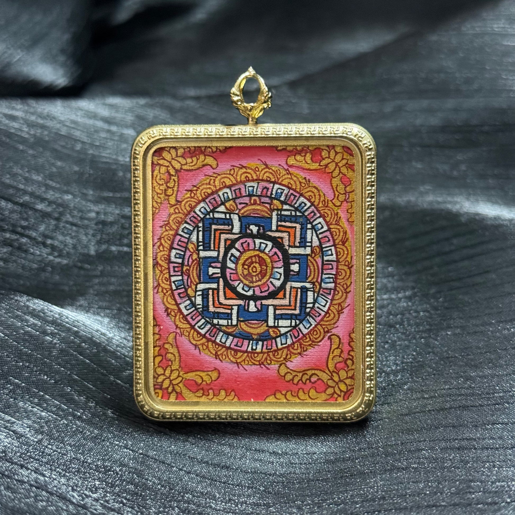 Hand-painted sacred mandala mini thangka pendant in a gold frame, featuring a traditional Buddhist mandala design with geometric patterns and symbolic cosmic structure.