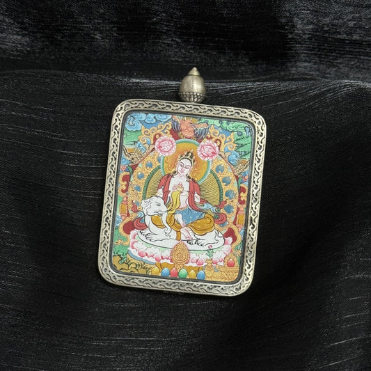 Angled view of Samantabhadra Bodhisattva thangka pendant showing mineral pigment layering, halo detailing, lotus base, white elephant mount, and engraved silver frame with top loop.
