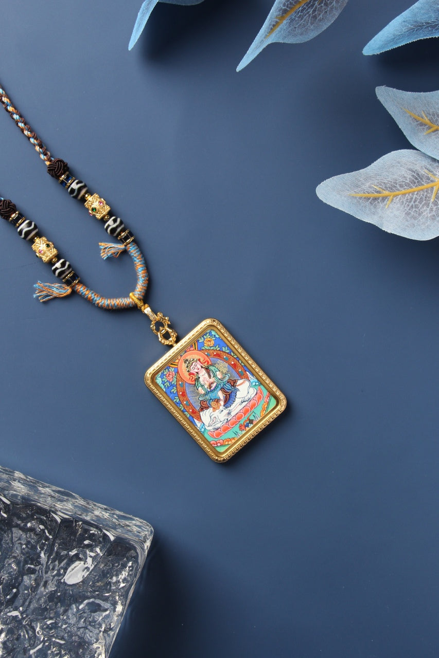Angled front view of the Samantabhadra Bodhisattva mini thangka pendant highlighting the hand-painted image, saturated mineral pigment layers, metal case thickness, textured border pattern, and clasp-to-bail hardware connection.