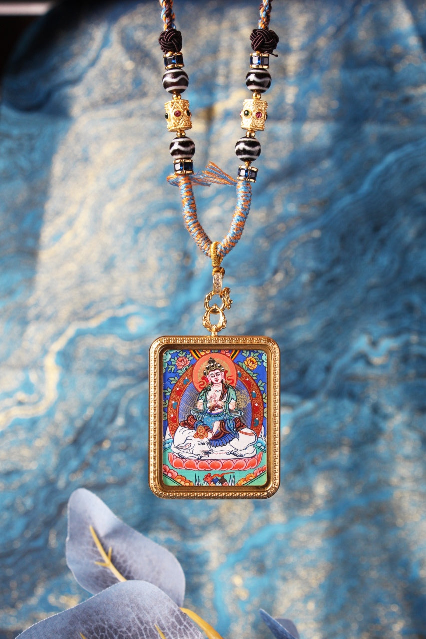 Close-up of the Samantabhadra Bodhisattva mini thangka pendant showing fine linework, detailed iconography, vivid mineral pigment colors, ornate frame border, and the bead-and-braided cord section near the pendant loop.