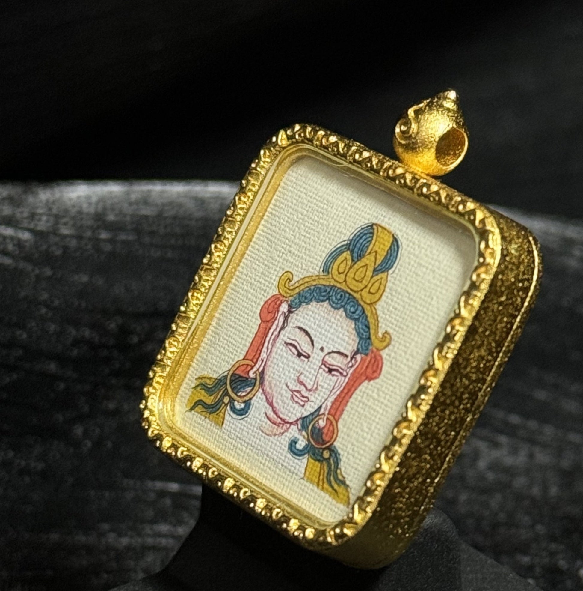 Close-up of Samantabhadra Bodhisattva miniature thangka painting with crown details and traditional Tibetan iconography mounted in a gold-toned square pendant frame.
