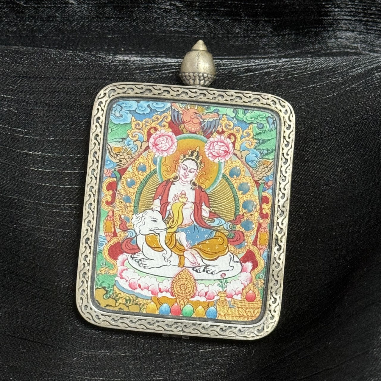 Close-up front view of Samantabhadra Bodhisattva Tibetan Miansa mini thangka pendant featuring elephant mount, circular halo, floral motifs, symbolic offerings, and engraved silver border.