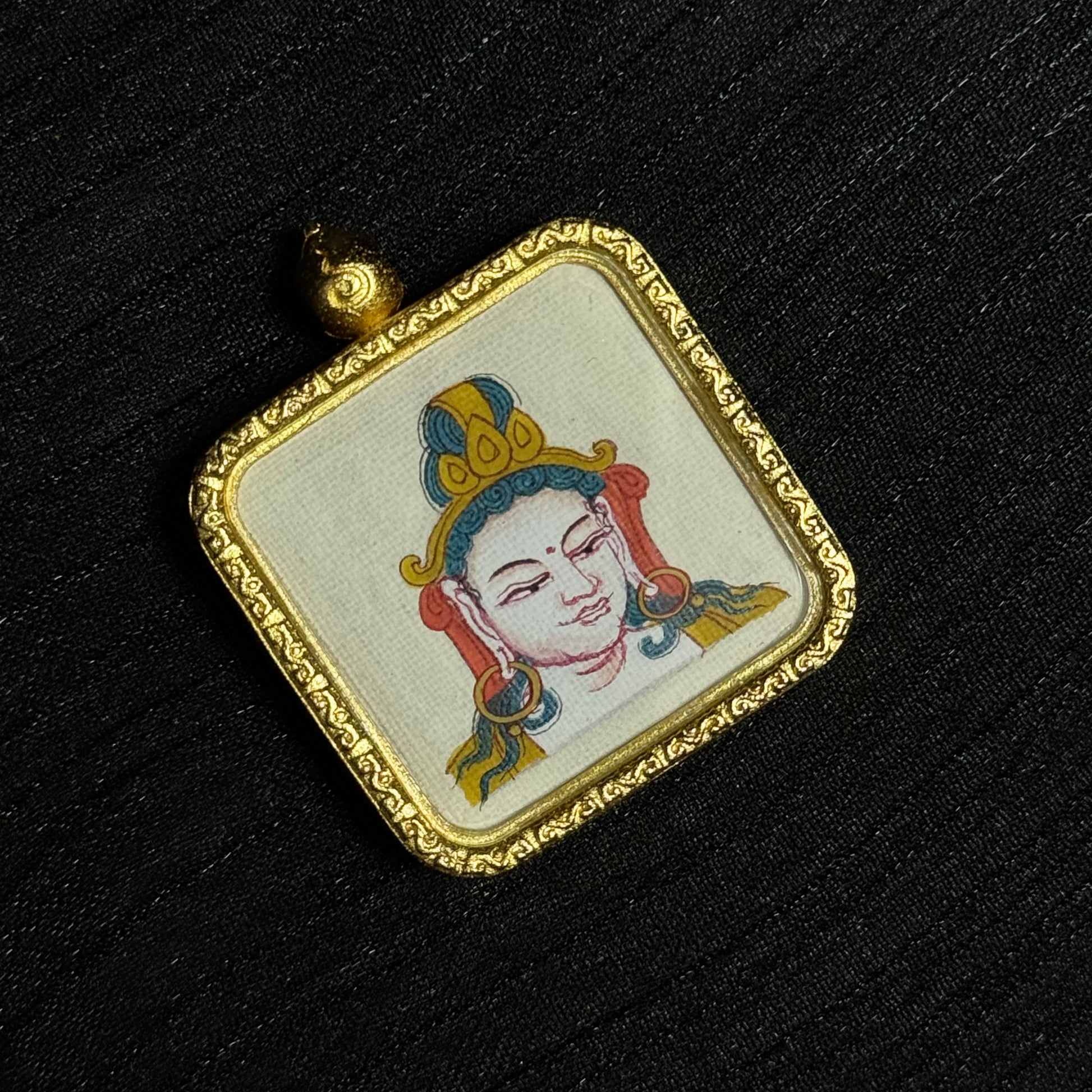 Samantabhadra Bodhisattva mini thangka pendant displayed on dark fabric background showing hand-painted deity portrait within a decorative gold pendant frame.