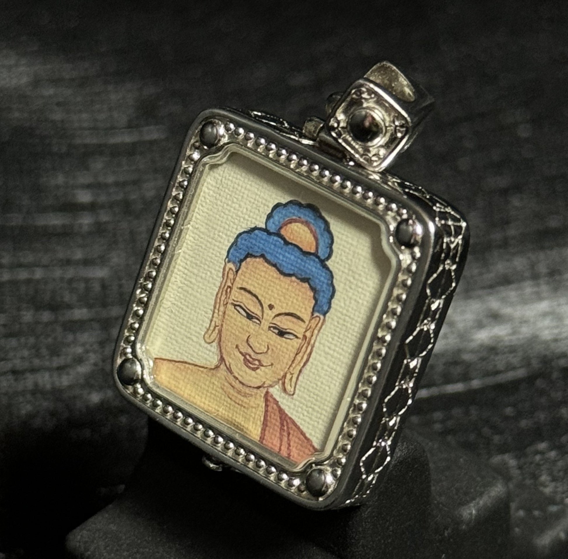 Side view of a miniature Amitabha Buddha thangka pendant highlighting the hand-painted artwork and decorative silver pendant structure.