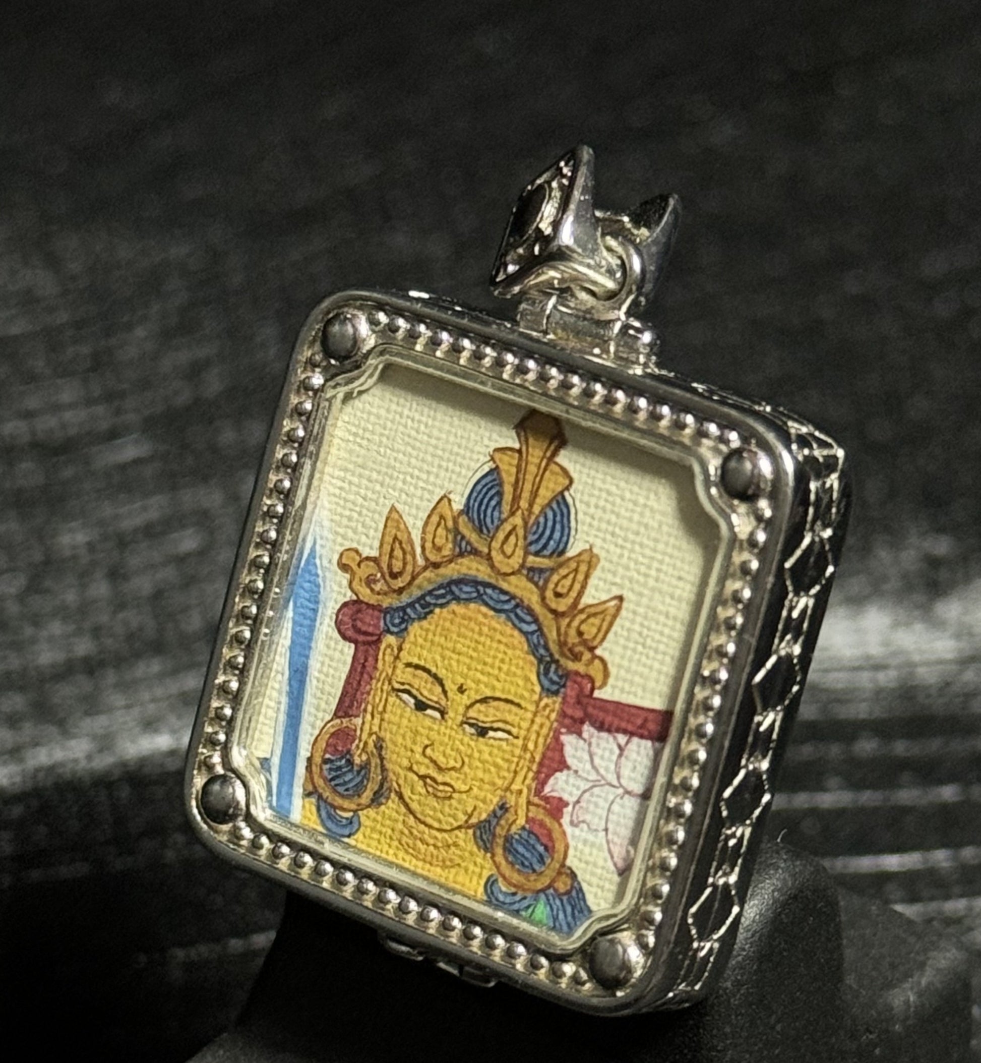 Side view of a Manjushri Bodhisattva miniature thangka pendant showing the hand-painted artwork and detailed silver pendant structure.