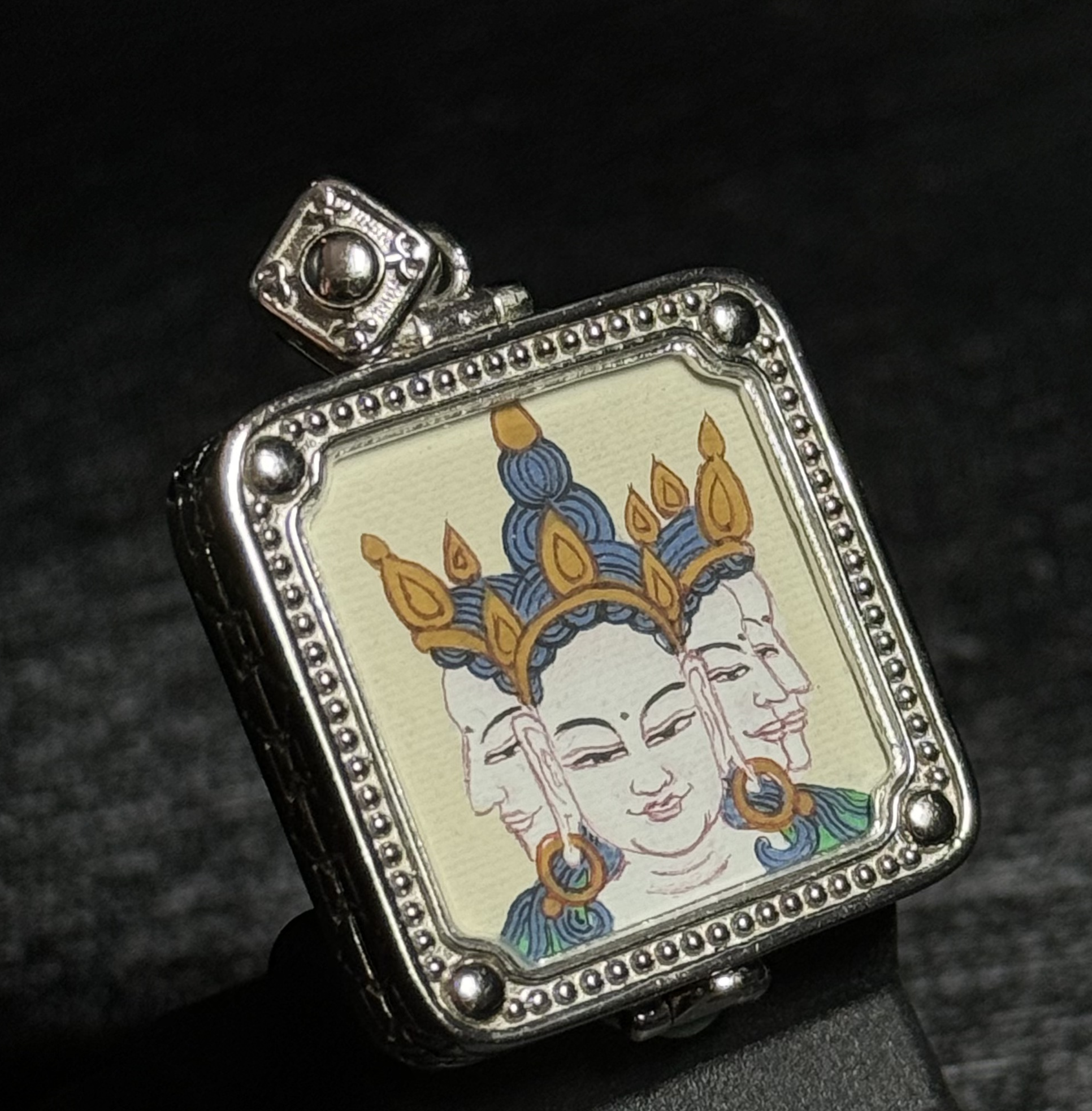 Side view of a Vairocana Buddha miniature thangka pendant showing the hand-painted artwork and detailed silver pendant structure.