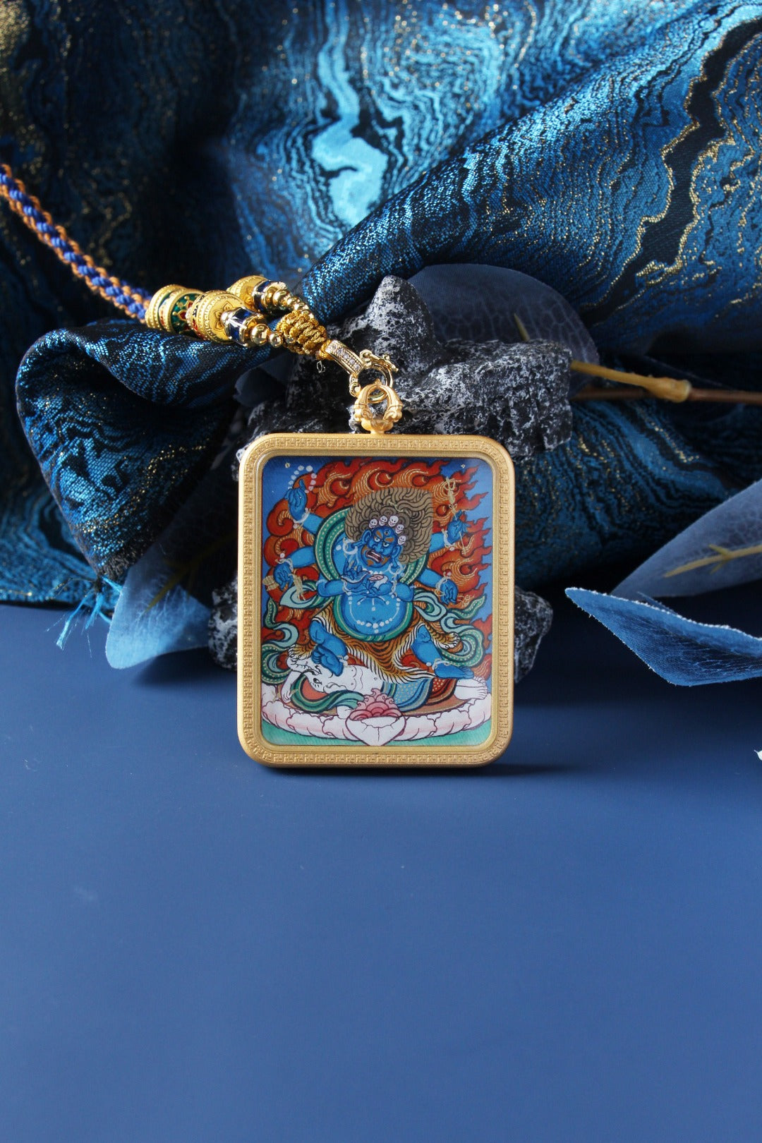 Close-up of a Six-Armed Mahakala mini thangka pendant featuring crisp linework, vivid mineral pigment colors, and a protective metal case with pendant loop and bead-and-cord attachment.