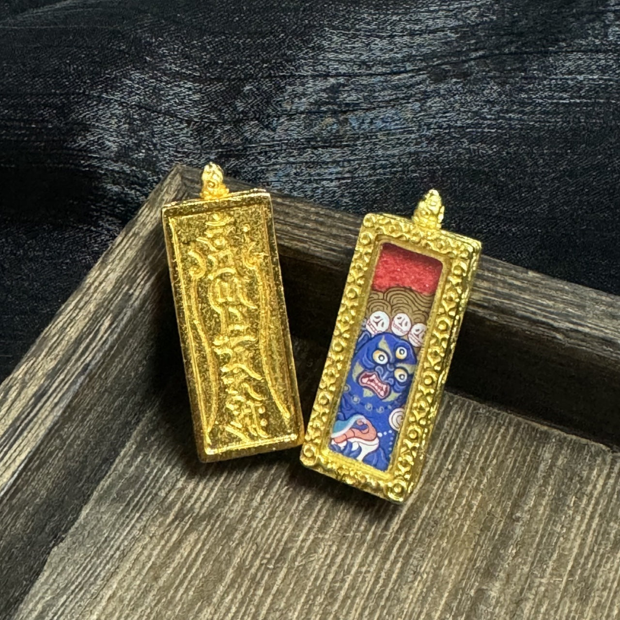 Front and back view of a Six-Armed Mahakala mini thangka pendant, showing the hand-painted blue wrathful face with multiple eyes, red upper background, and gold-tone raised frame, alongside the back of the copper case with embossed script texture.