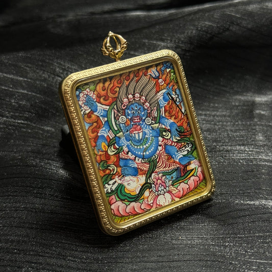 Hand-painted Six-Armed Mahakala mini thangka pendant in a gold pendant frame, showing the fierce blue protector deity surrounded by flames and traditional Himalayan iconography.