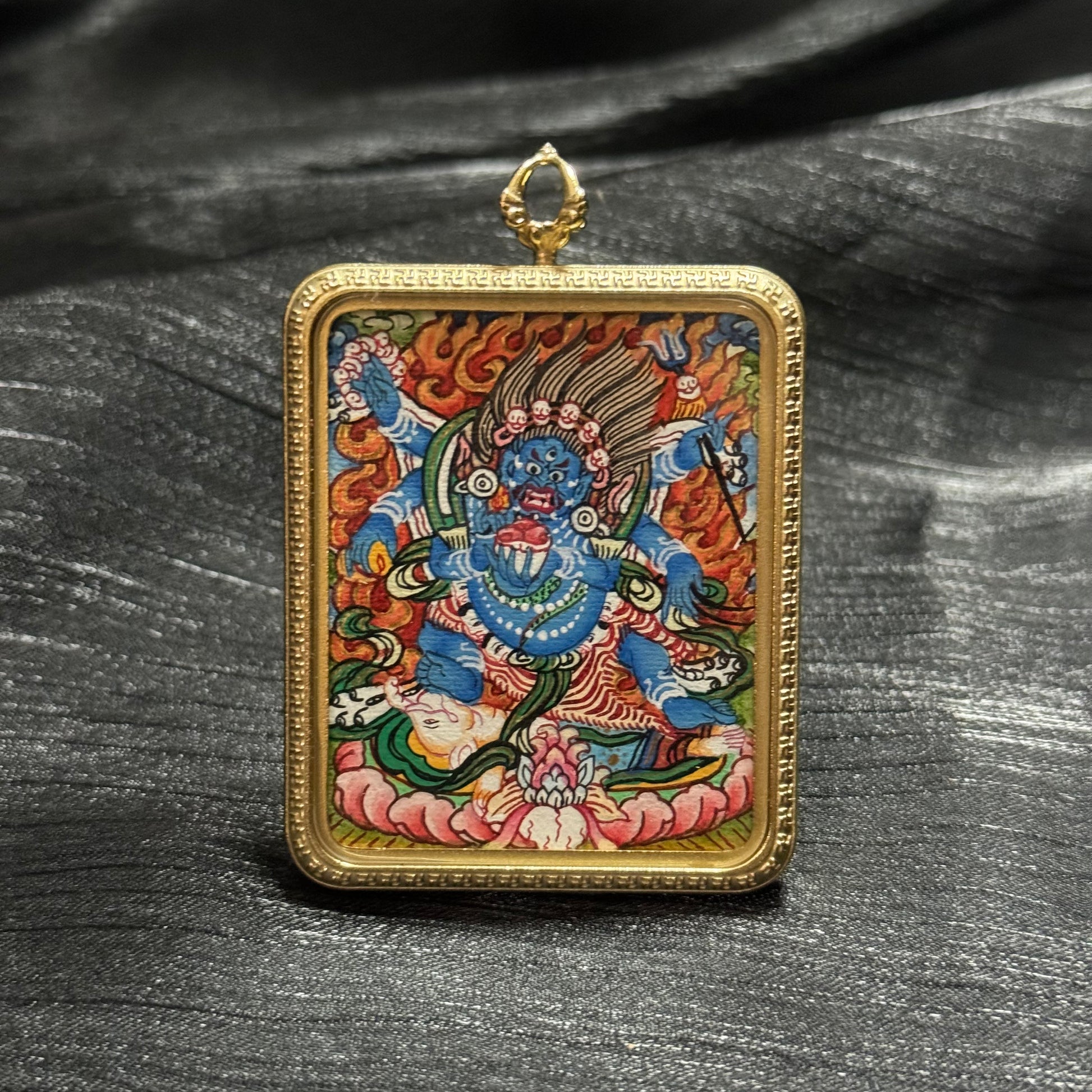 Front view of a Six-Armed Mahakala miniature thangka pendant in a gold frame, depicting the wrathful protector deity standing within flames in traditional Tibetan Buddhist iconography.