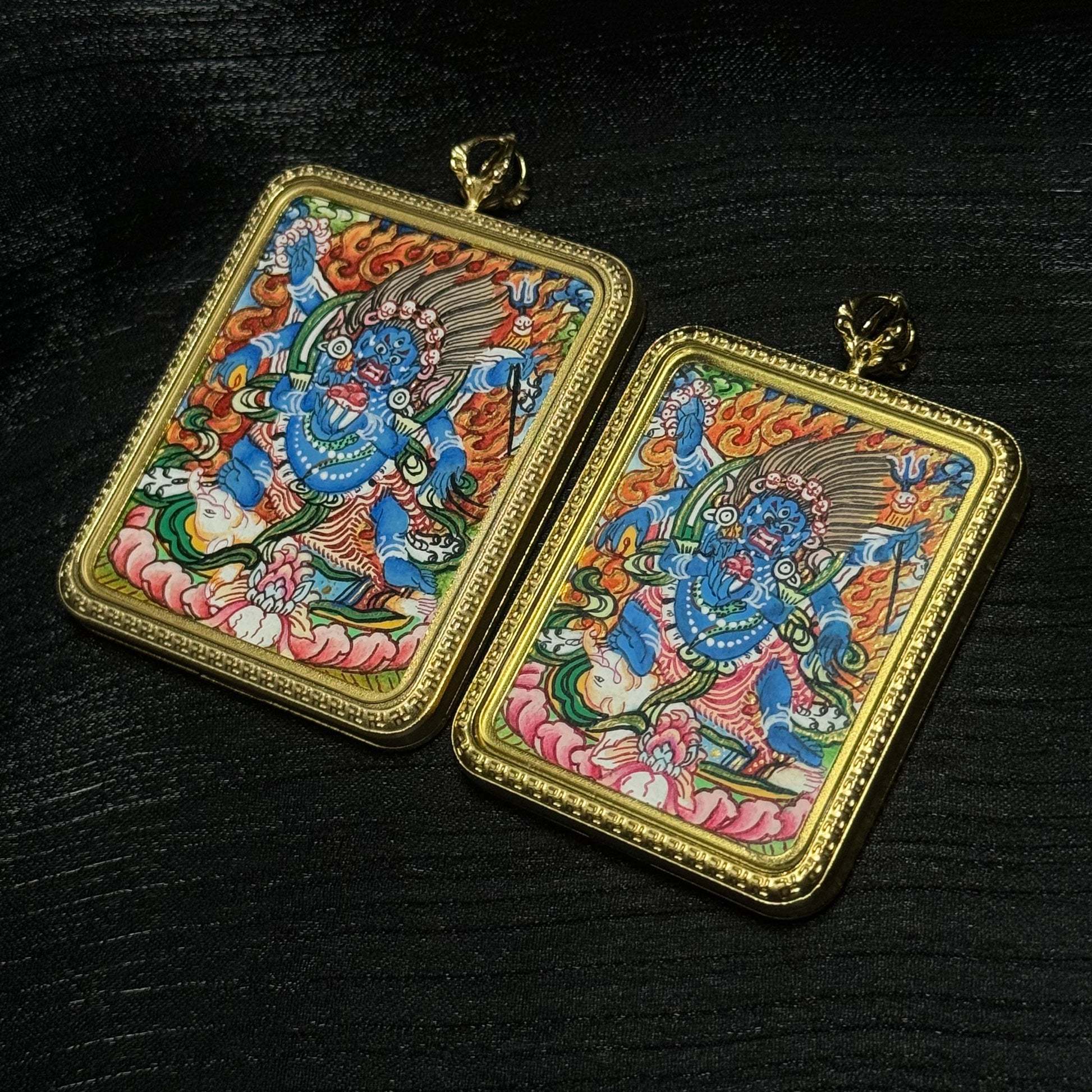 Two Six-Armed Mahakala hand-painted mini thangka pendants displayed together, showing detailed Himalayan Buddhist protector imagery in gold pendant frames.