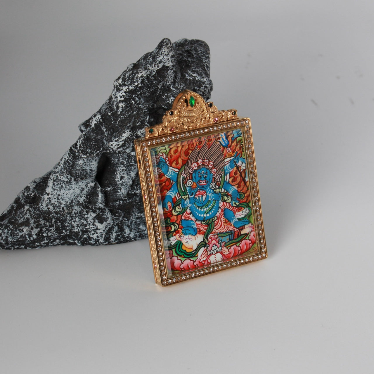 Straight-on view of the Six-Armed Mahakala mini thangka pendant highlighting vivid hand-painted details, layered mineral pigment colors, and the rectangular crystal-set frame.