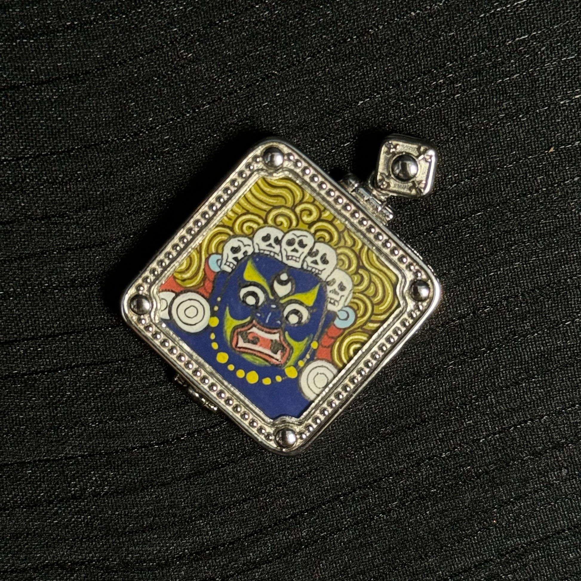 Close angled view of Six-Armed Mahakala miniature thangka pendant highlighting Tibetan painting details and mineral pigment layers