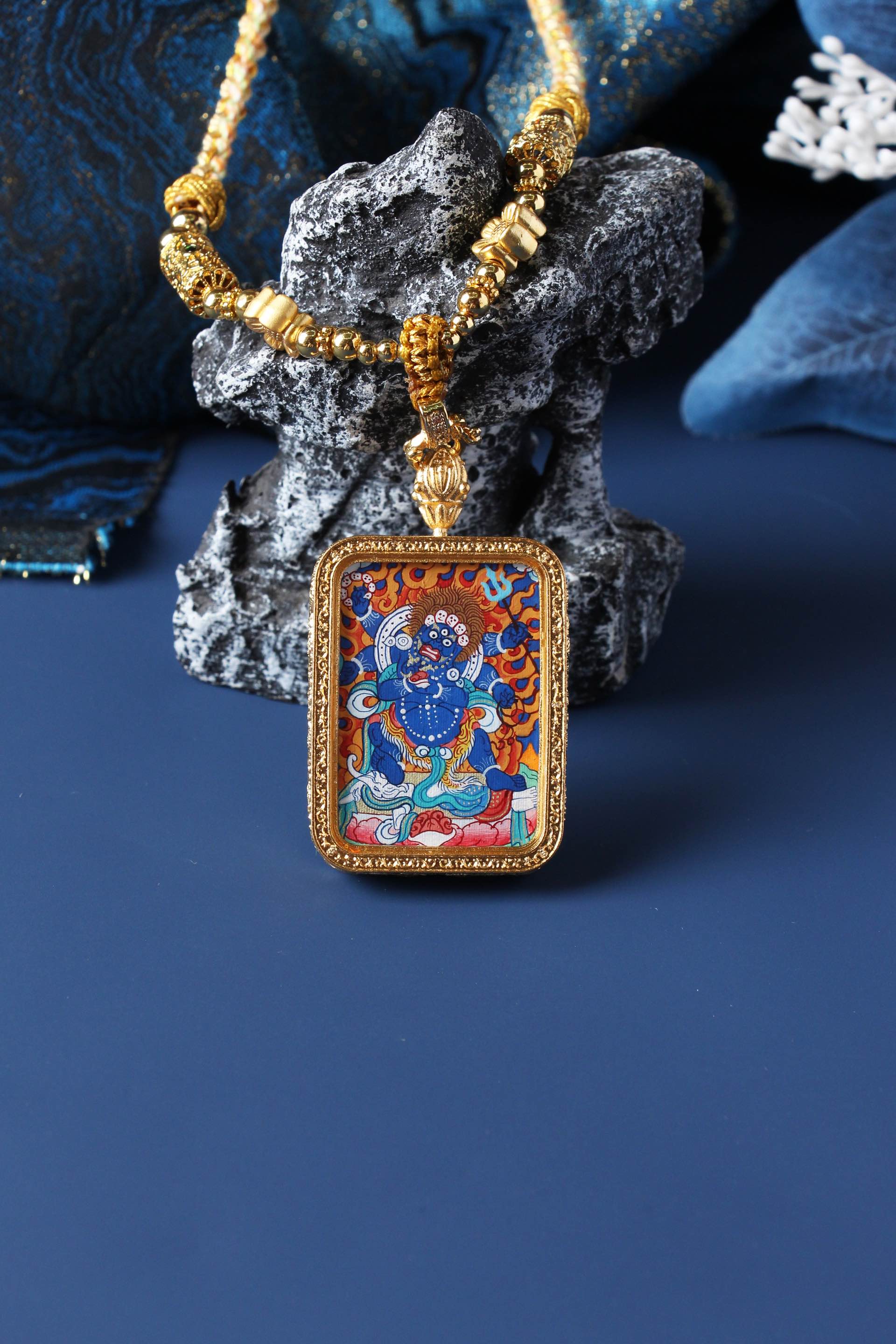 Six-Armed Mahakala mini thangka pendant photographed upright, highlighting rectangular gold-tone double-sided metal case and vivid mineral pigment colors