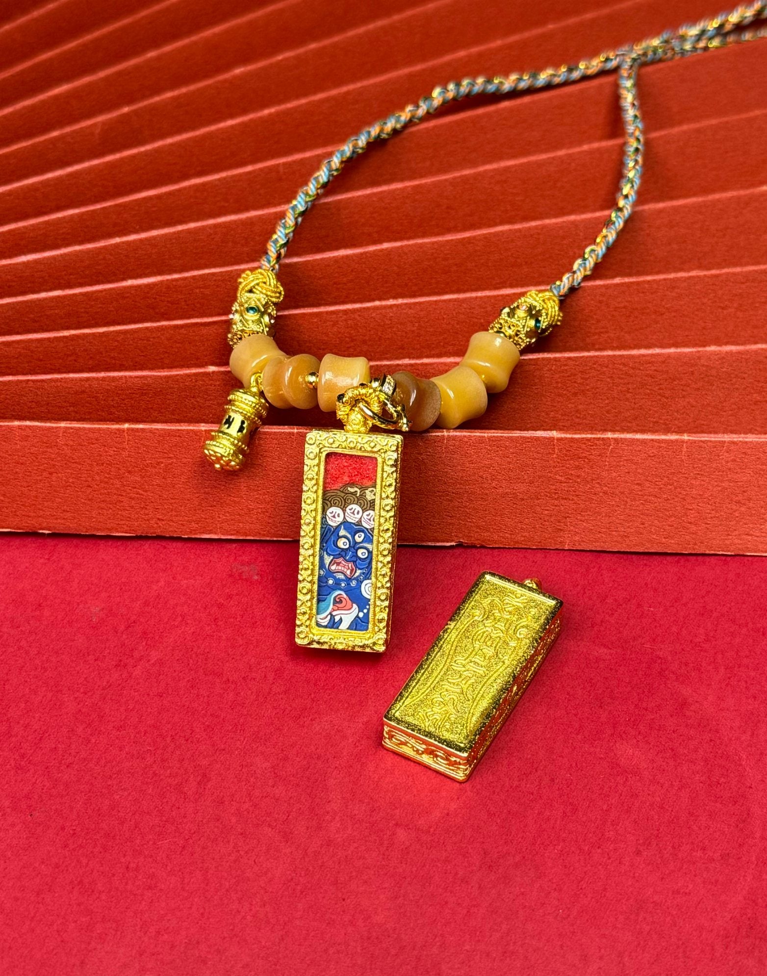 Six-Armed Mahakala mini thangka inside decorative copper gawu pendant case displayed with removable protective lid and braided necklace cord