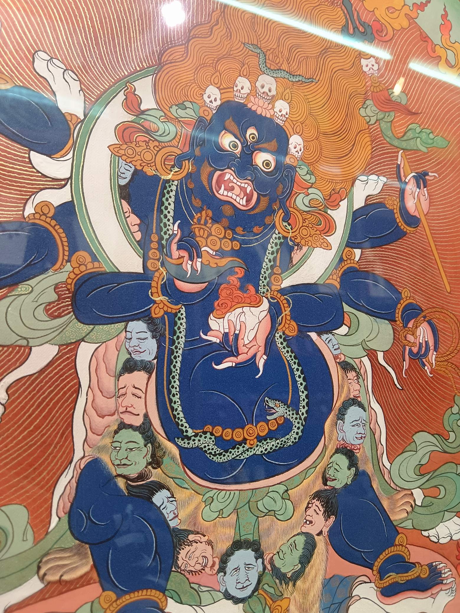 Close-up of the Six-Armed Mahakala face and torso showing layered mineral pigments, expressive facial features, and detailed Tibetan thangka brushwork.