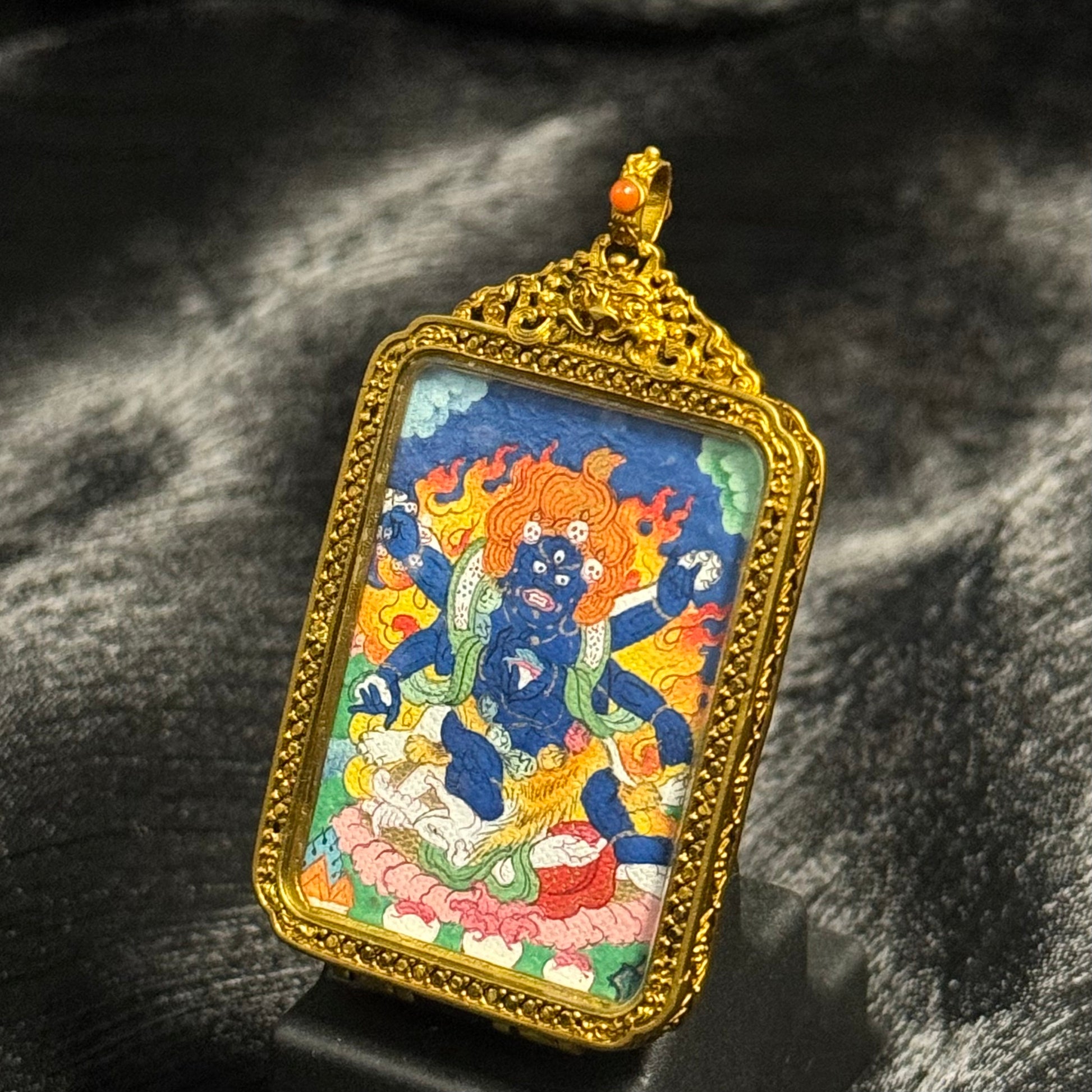 Close view of Six-Armed Mahakala miniature thangka painting with vibrant mineral pigment colors inside traditional copper pendant frame