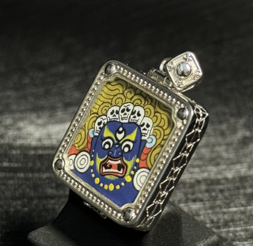Angled view of Six-Armed Mahakala mini thangka pendant showing detailed Tibetan protector deity painting with vivid mineral pigment colors