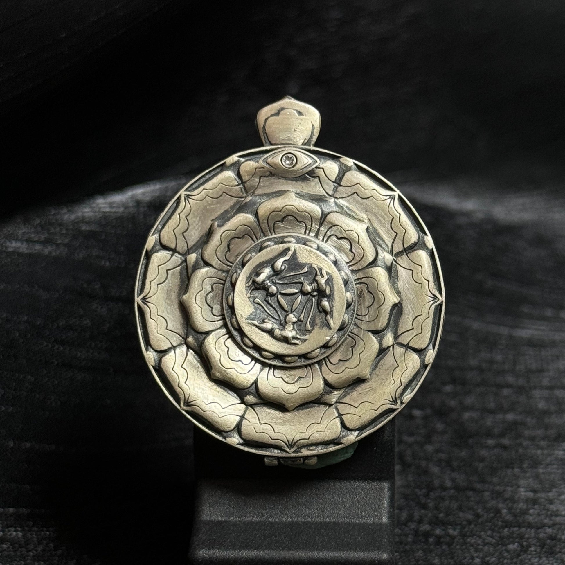 Back view of the mini thangka pendant showing the carved silver protective case with the traditional Three Hares shared-ear symbol design.