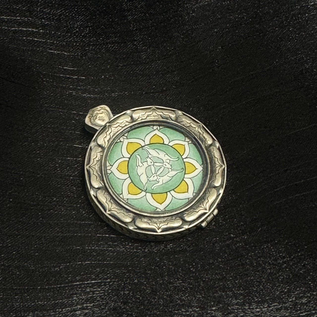 Front view of Three Hares with Shared Ears mini thangka pendant, green mineral pigment background with yellow lotus petals, hand-drawn three hare motif, 925 silver case with sculpted rim