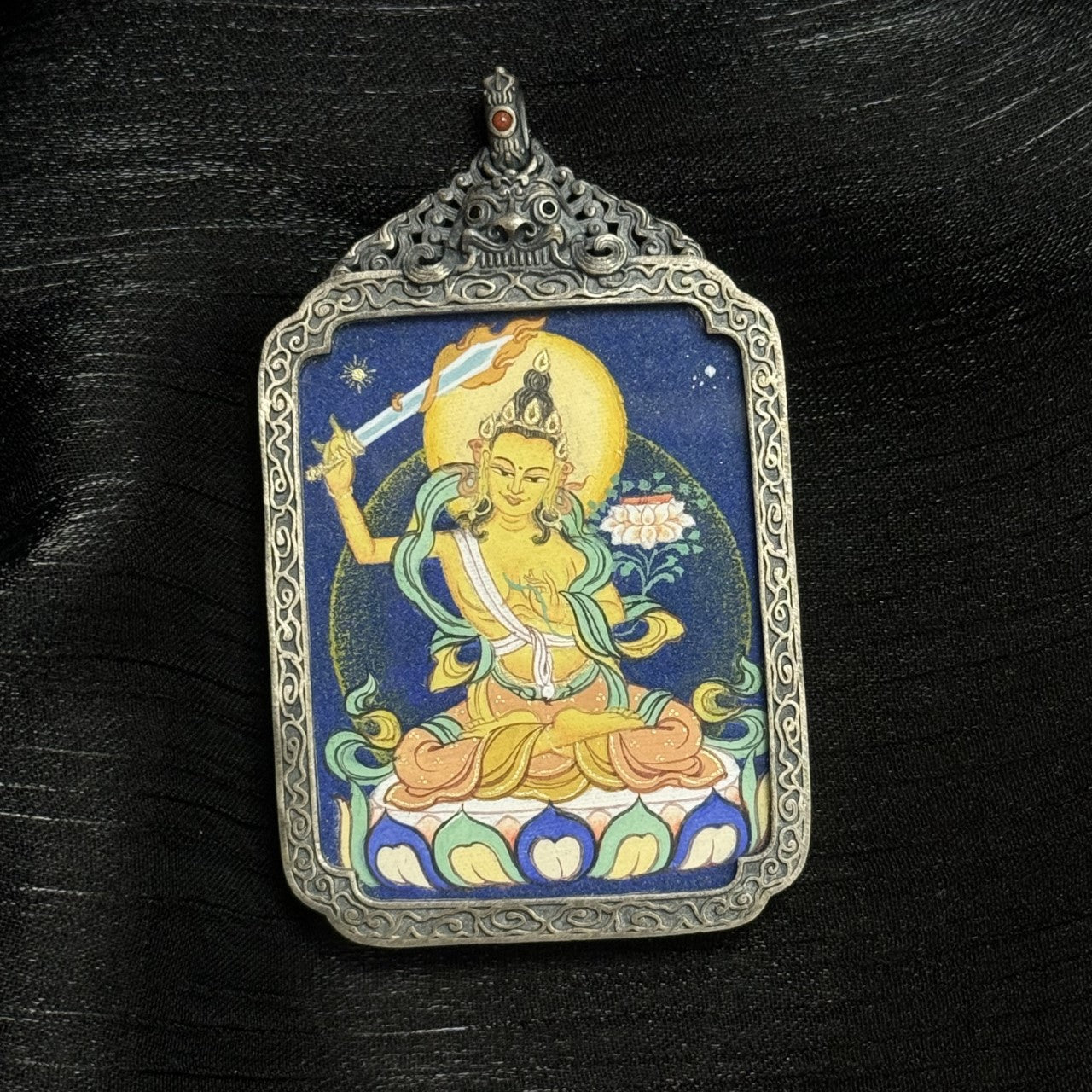 Full composition of Manjushri Bodhisattva mini thangka pendant, featuring deep blue background, circular aureole, carved silver border, and traditional Tibetan iconography.