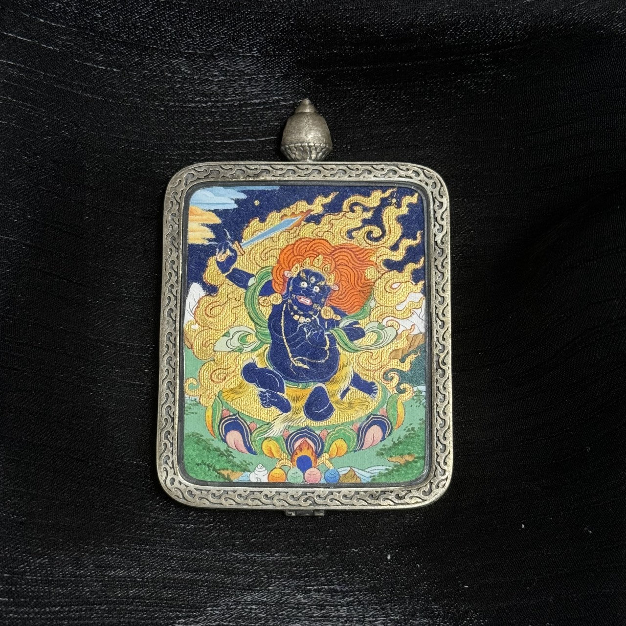 Front display of Acalanatha Tibetan mini thangka pendant highlighting traditional mineral pigment painting and decorative silver frame