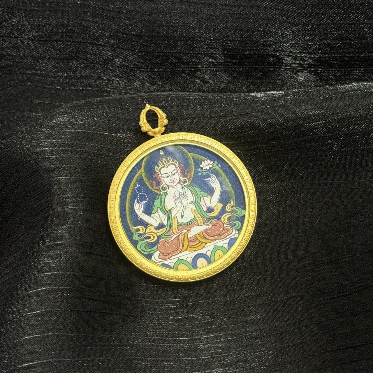 Tibetan round mini thangka pendant depicting Four-Armed Avalokiteshvara, featuring traditional iconography, mineral pigments, and fine hand-painted details