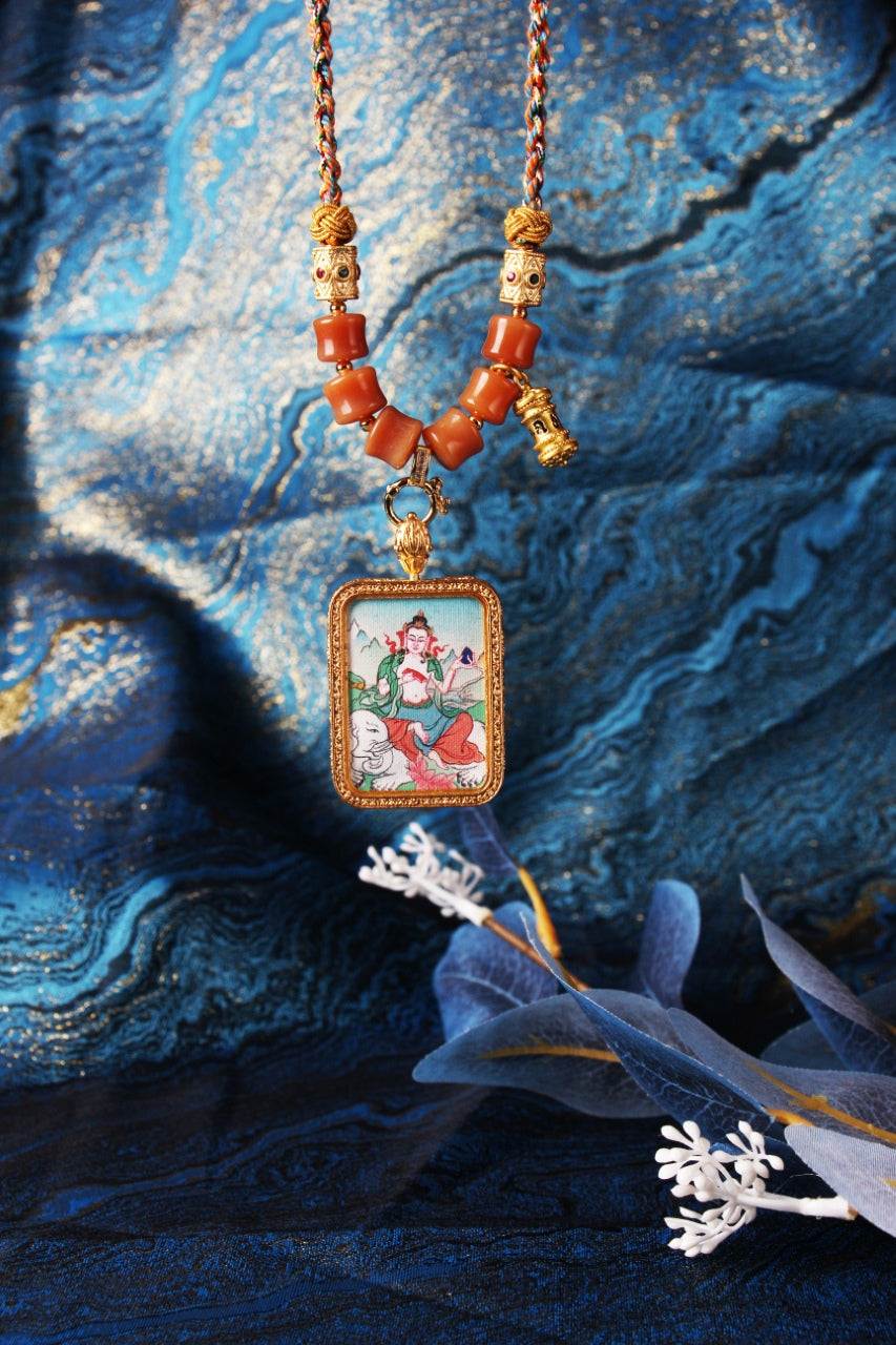 Hand-painted Tibetan Samantabhadra Bodhisattva mini thangka pendant presented on textured fabric background, highlighting mineral pigments and metal frame details