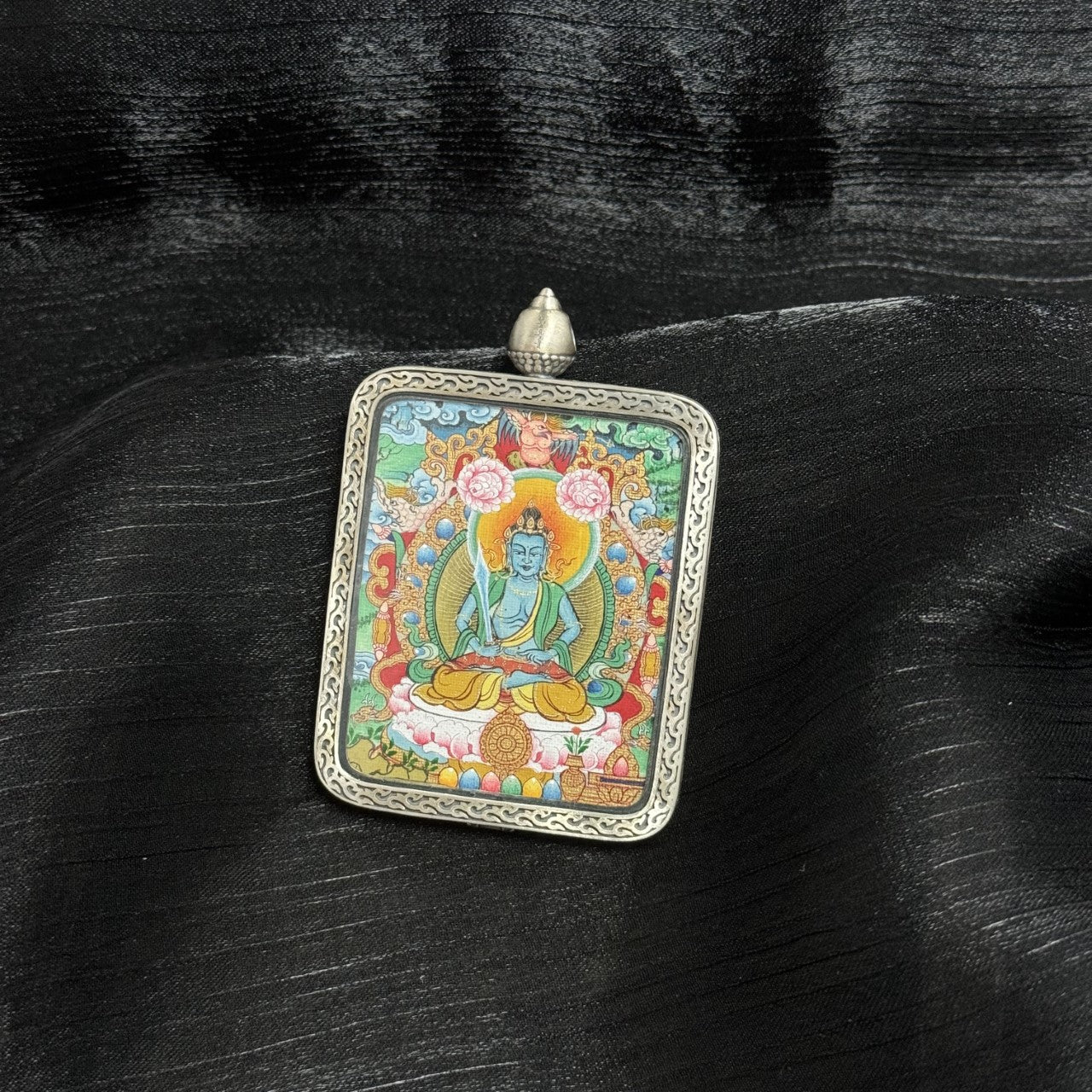 Close-up front view of Akasagarbha Bodhisattva mini thangka pendant highlighting facial detailing, sacred proportions, lotus platform, decorative background elements, and Dunhuang silver casing texture.