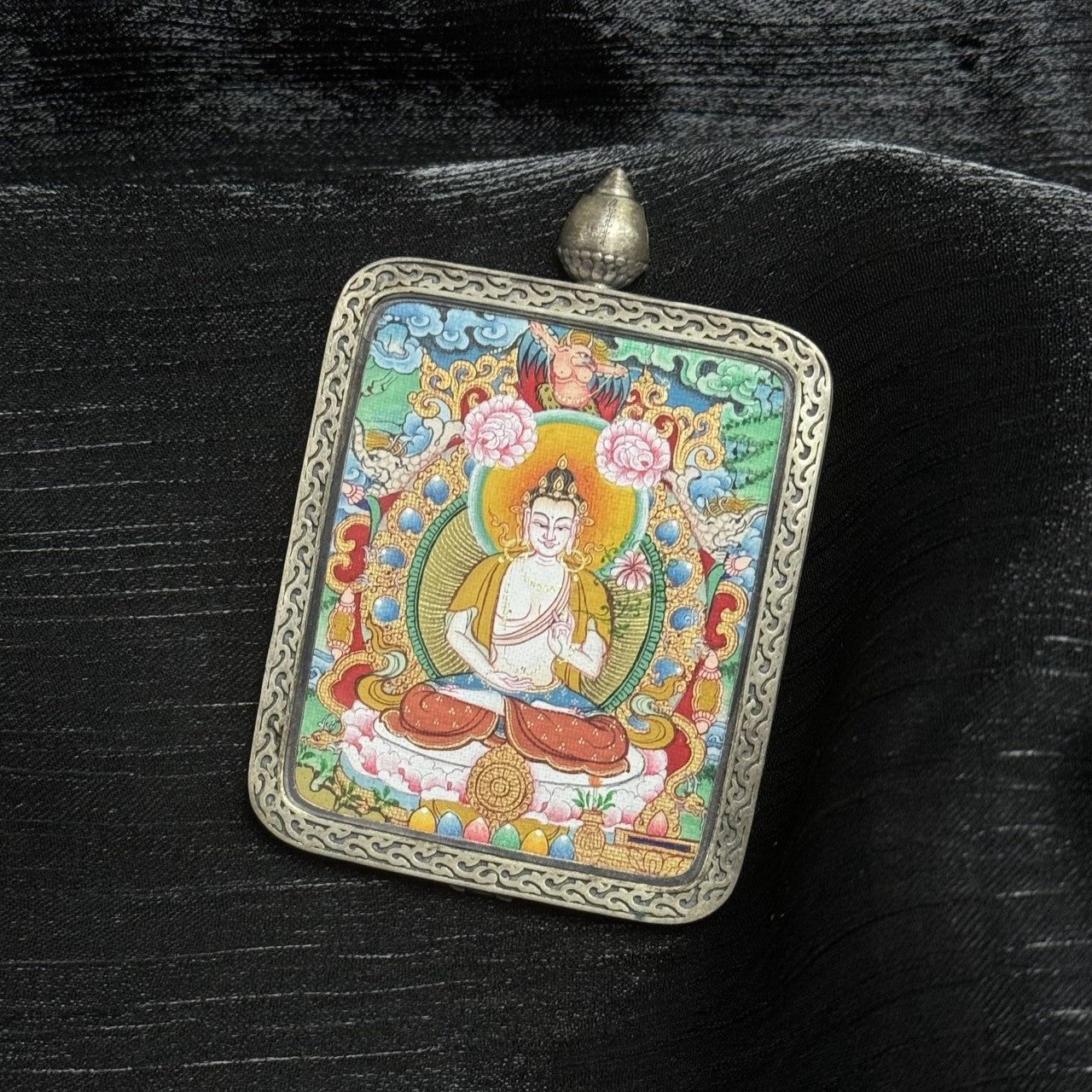 Side perspective of Mahasthamaprapta Bodhisattva mini thangka pendant highlighting color saturation, detailed iconography, Dunhuang silver casing texture, and dimensional framing.
