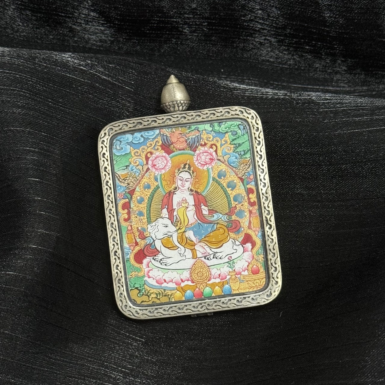 Side perspective of Samantabhadra Bodhisattva mini thangka pendant highlighting color saturation, detailed iconography, white elephant base, and textured Dunhuang silver casing.