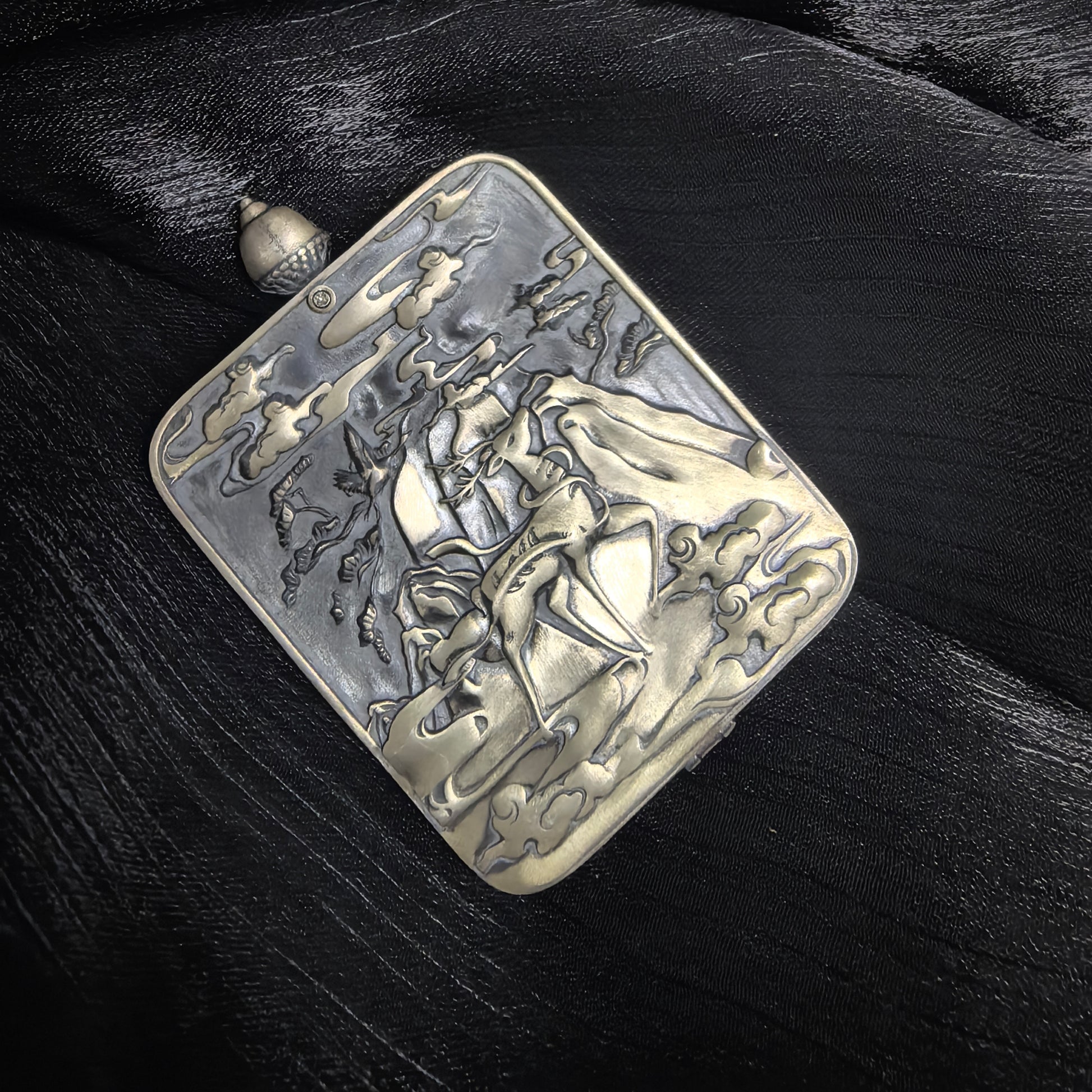 Back view of a Tibetan mini thangka pendant featuring a detailed metal relief design with mountain and landscape motifs.