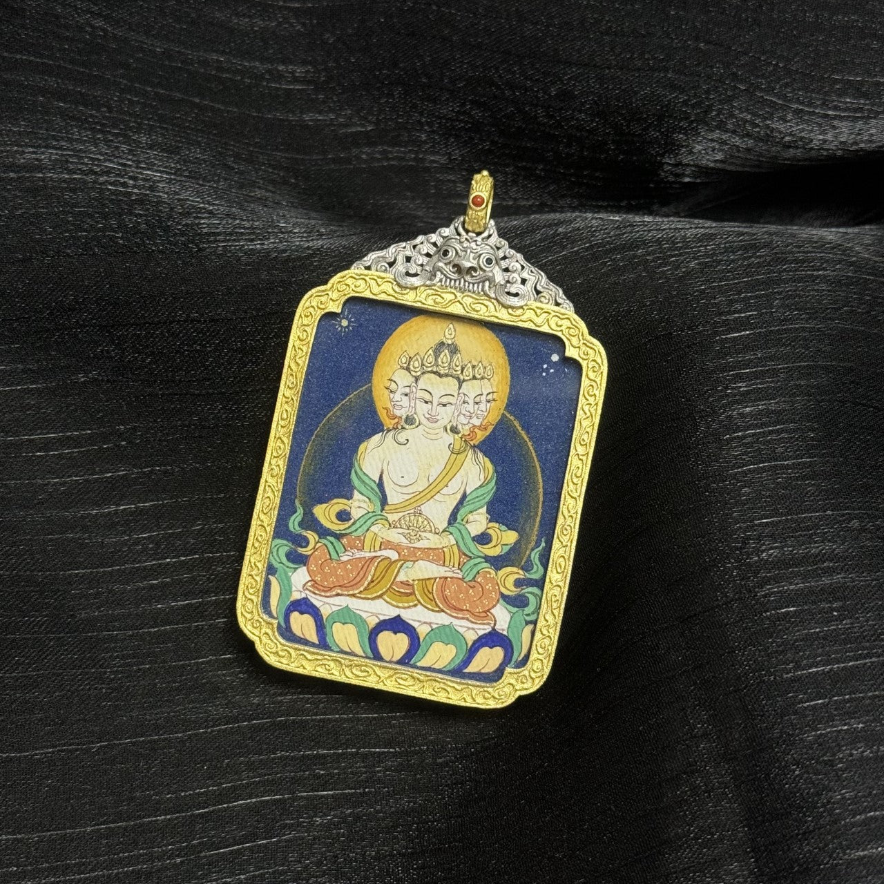 Full view of a Tibetan Vairocana Buddha mini thangka pendant, depicting the five-faced Buddha seated on a lotus throne, painted with traditional mineral pigments.